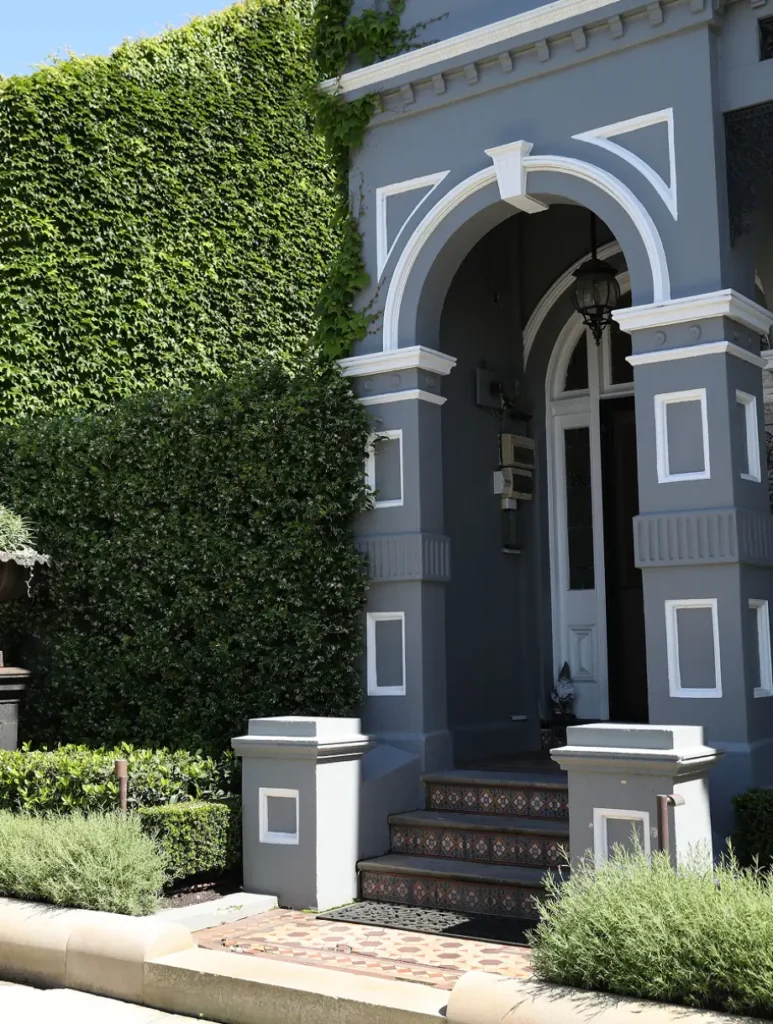 A stately dark grey home exterior featuring a dramatic white arched portico entrance.